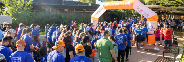 Walk With Me 2023 participants walking through starting line arch