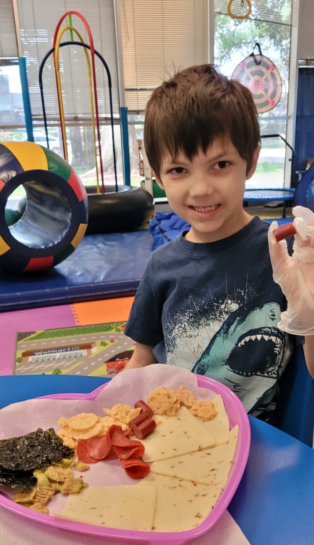 Zachary smiling during Food Science and Exploration Occupational Therapy session