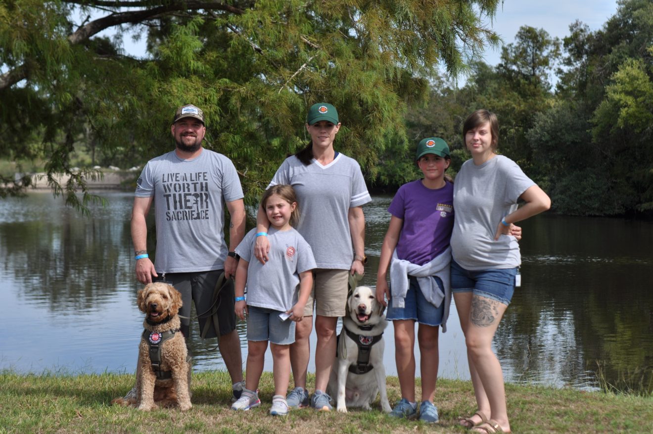 Veteran Family at camp standing in front of lake with service dogs