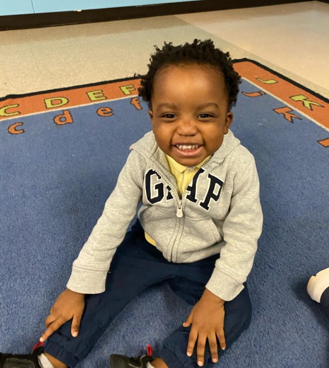 ECI Client Levi sitting on the floor with a BIG smile