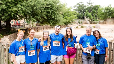 YAC students and parents standing in front of a Houston Zoo exhibit at Walk With Me 2024.