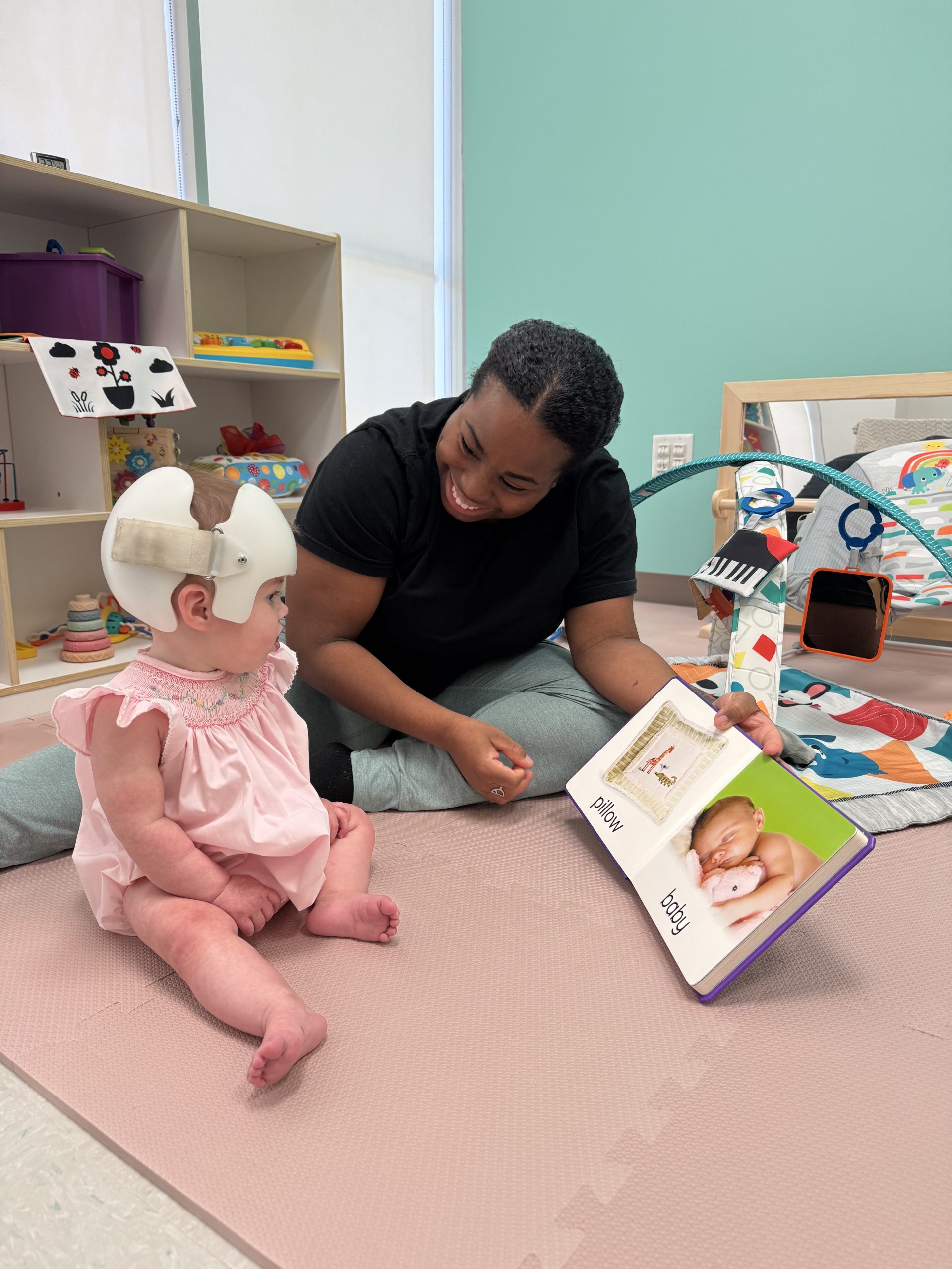 Teacher reading to baby on the floor.