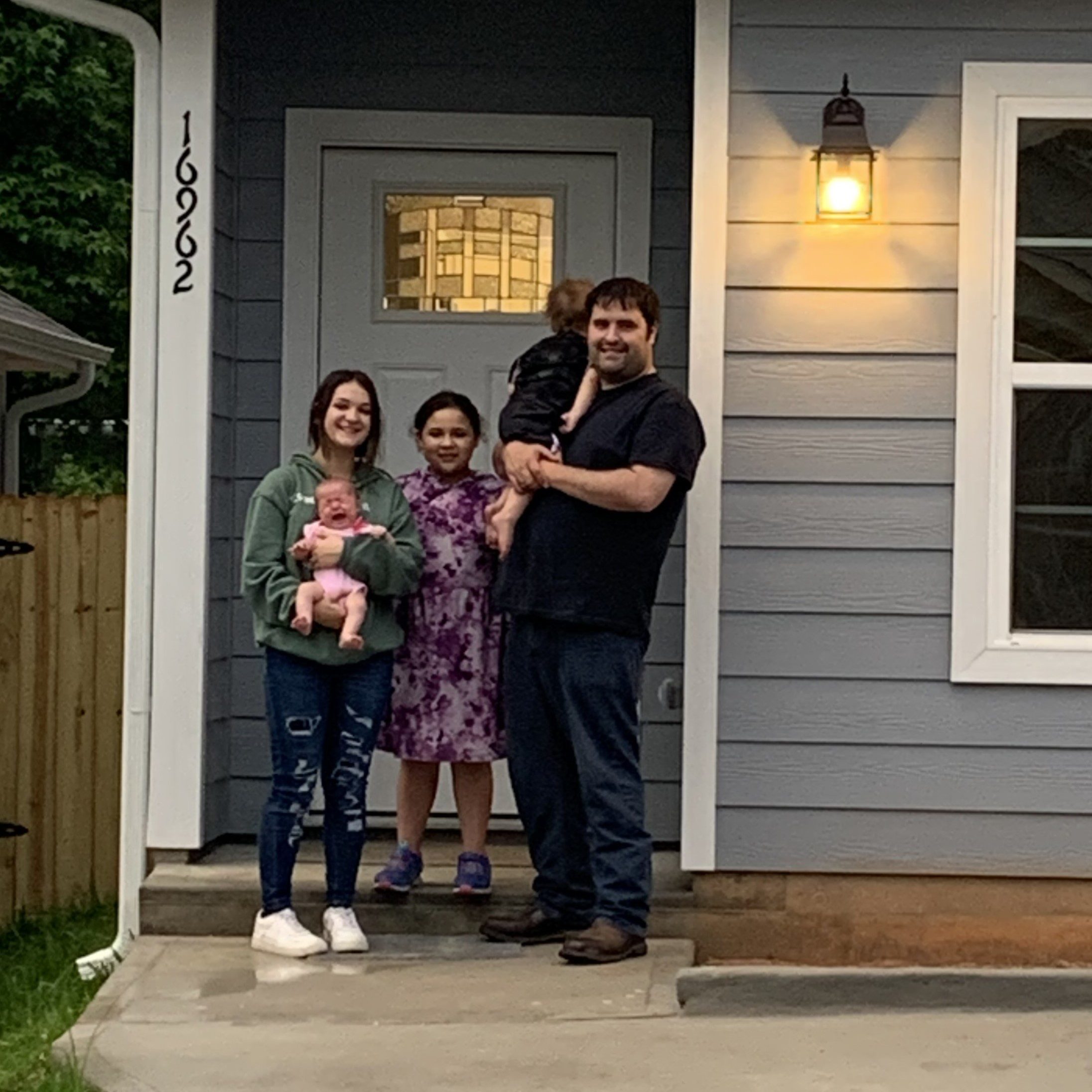 A young family standing in the doorway of their first home.